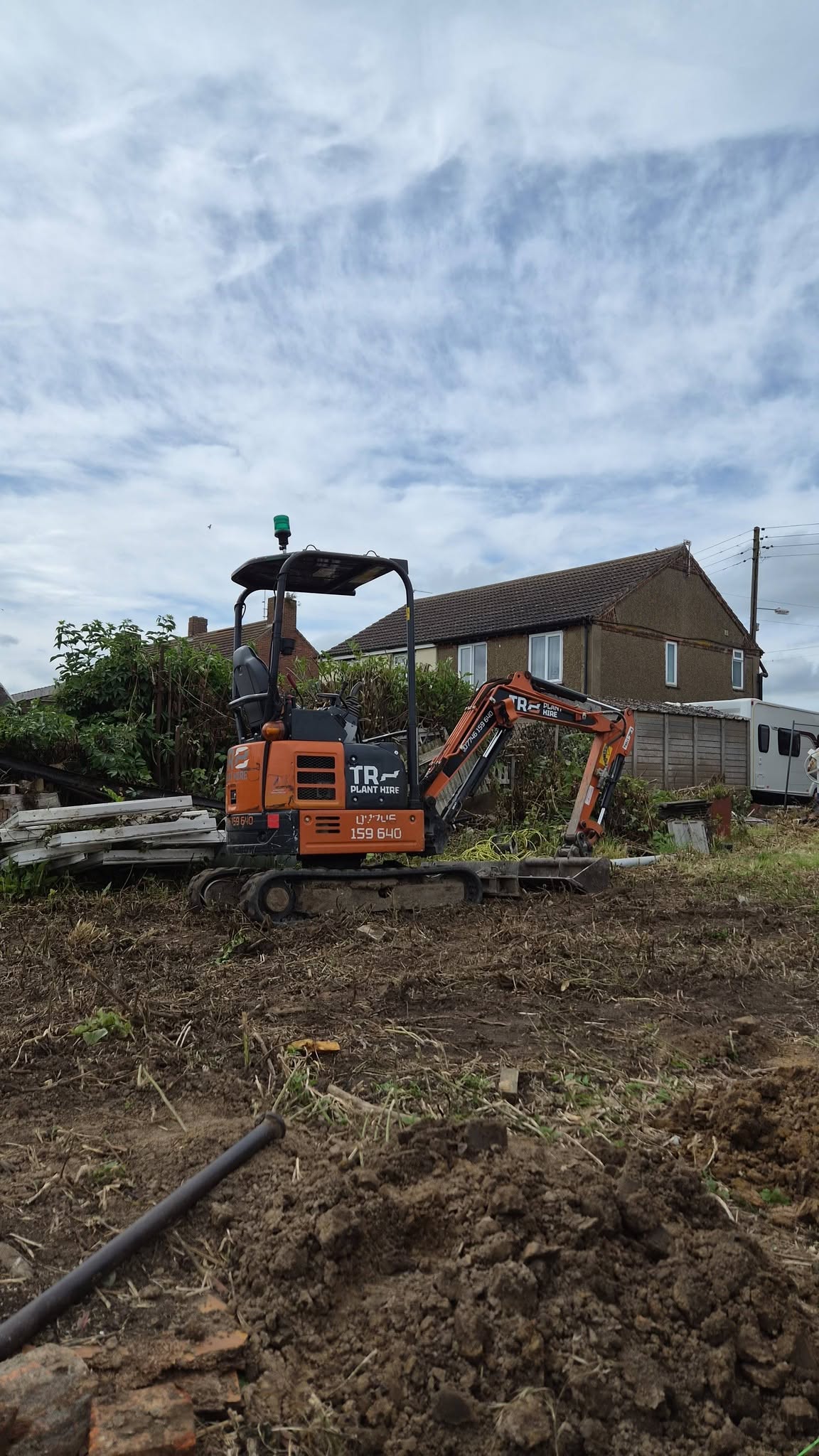 A mini digger clearing ground on a residential site