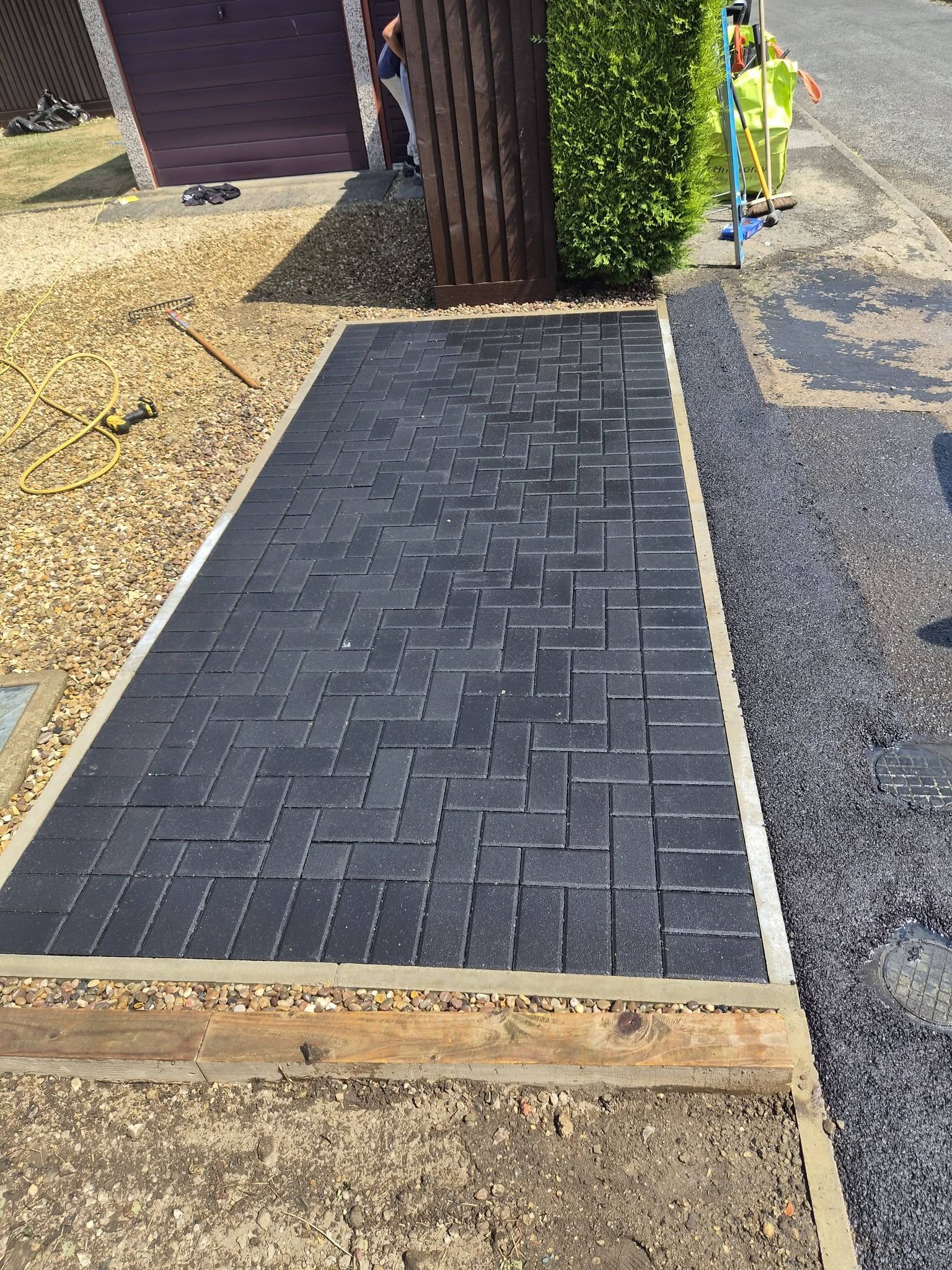 A charcoal block-paved path laid in a herringbone pattern beside a house
