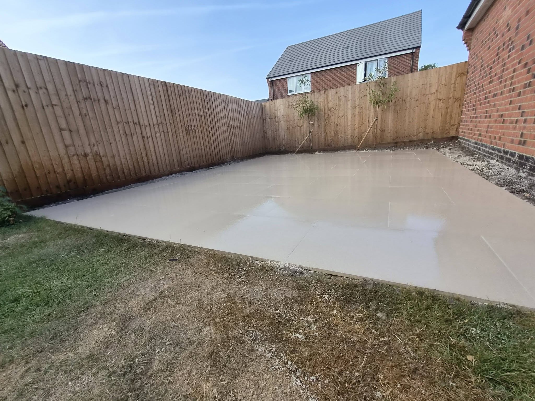 A large pale porcelain patio enclosed by new timber fencing