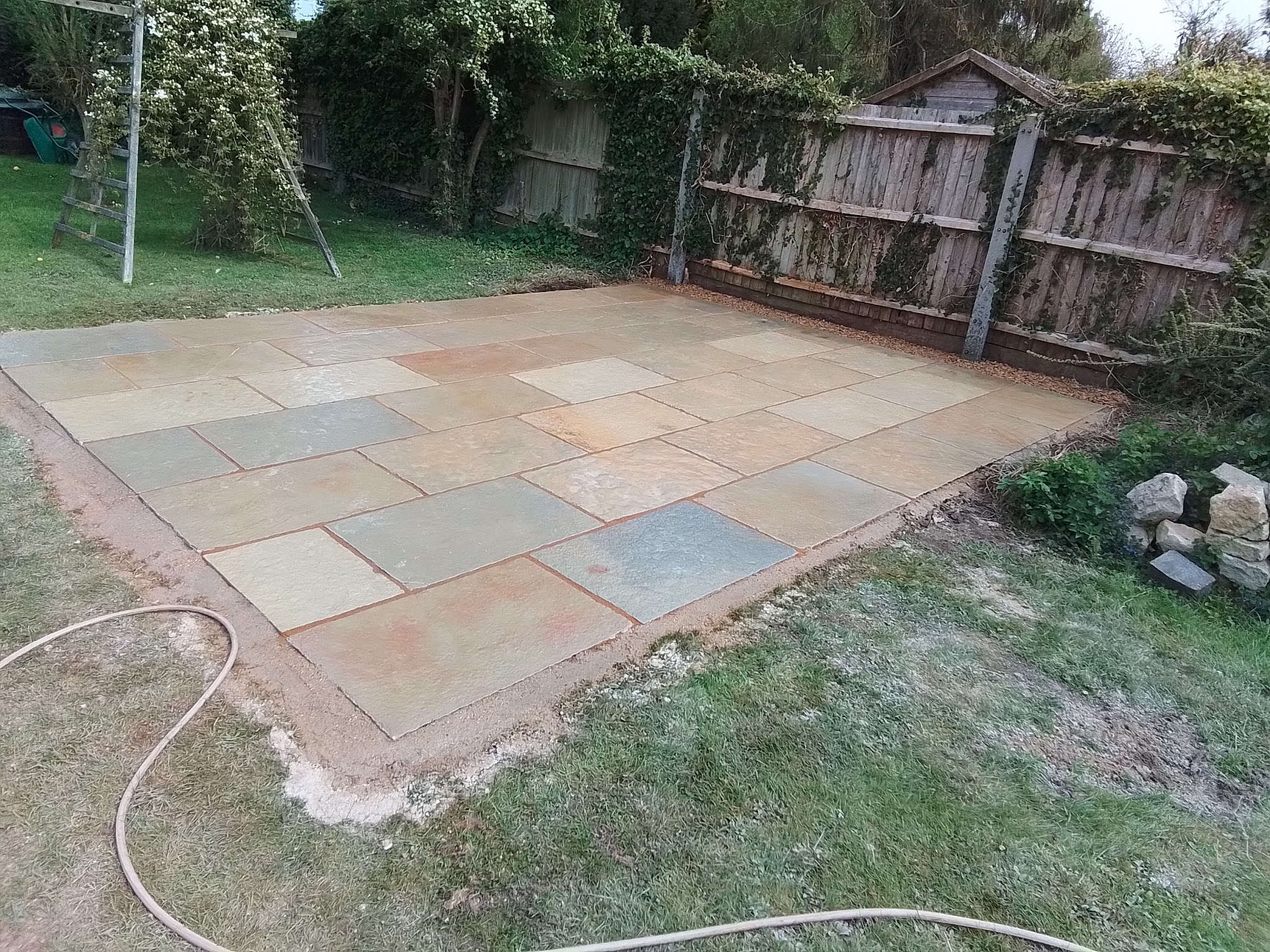 A newly laid Indian sandstone patio set into a lawn