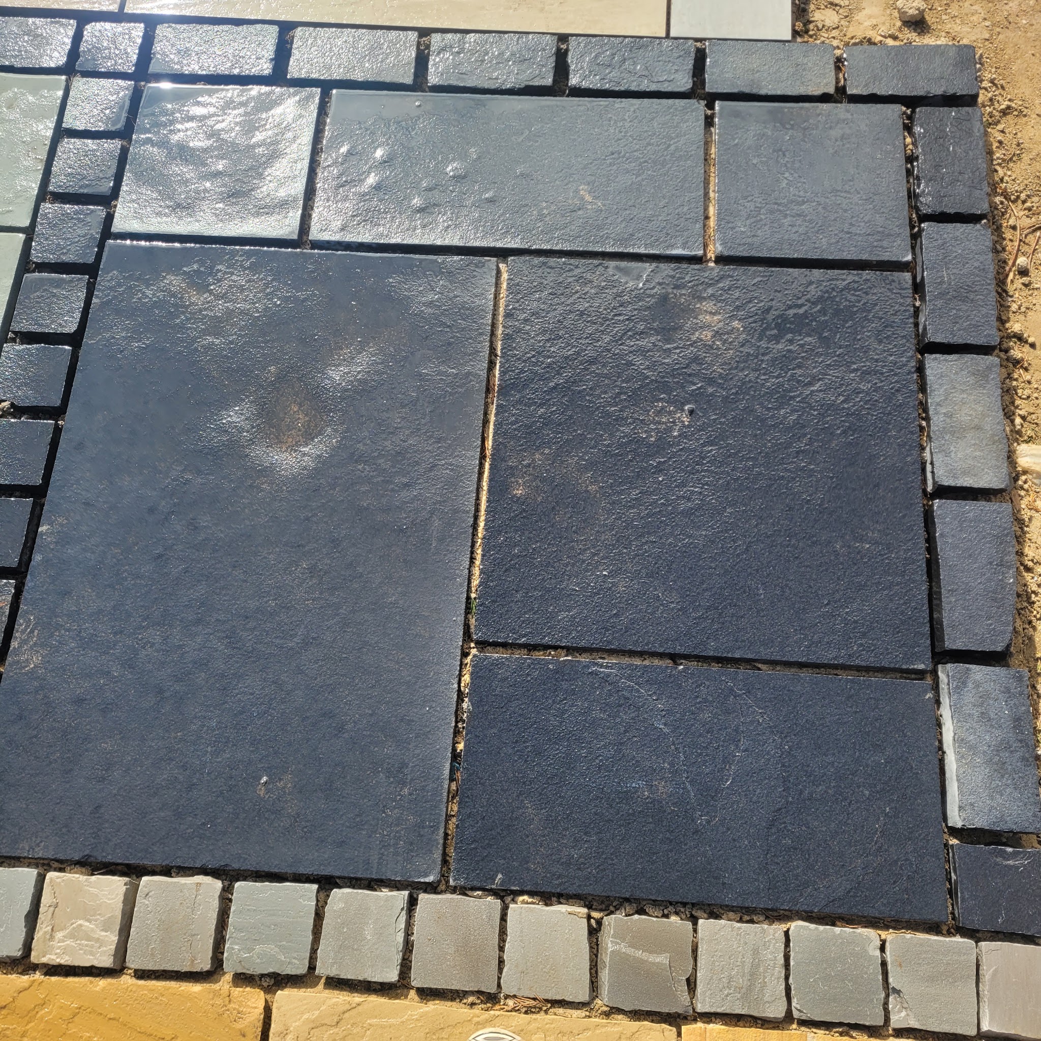 Dark slate paving slabs framed by a border of small setts