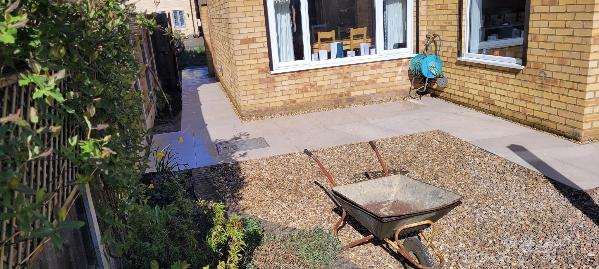 A new patio and gravel area along the back of a brick house